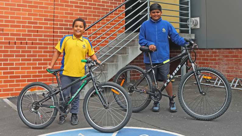 Two students from Albuera Street Primary School holding bicycles