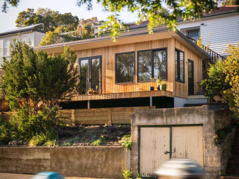 A tiny home secondary residence sharing a property with the main house, some cyclists bike in the foreground.
